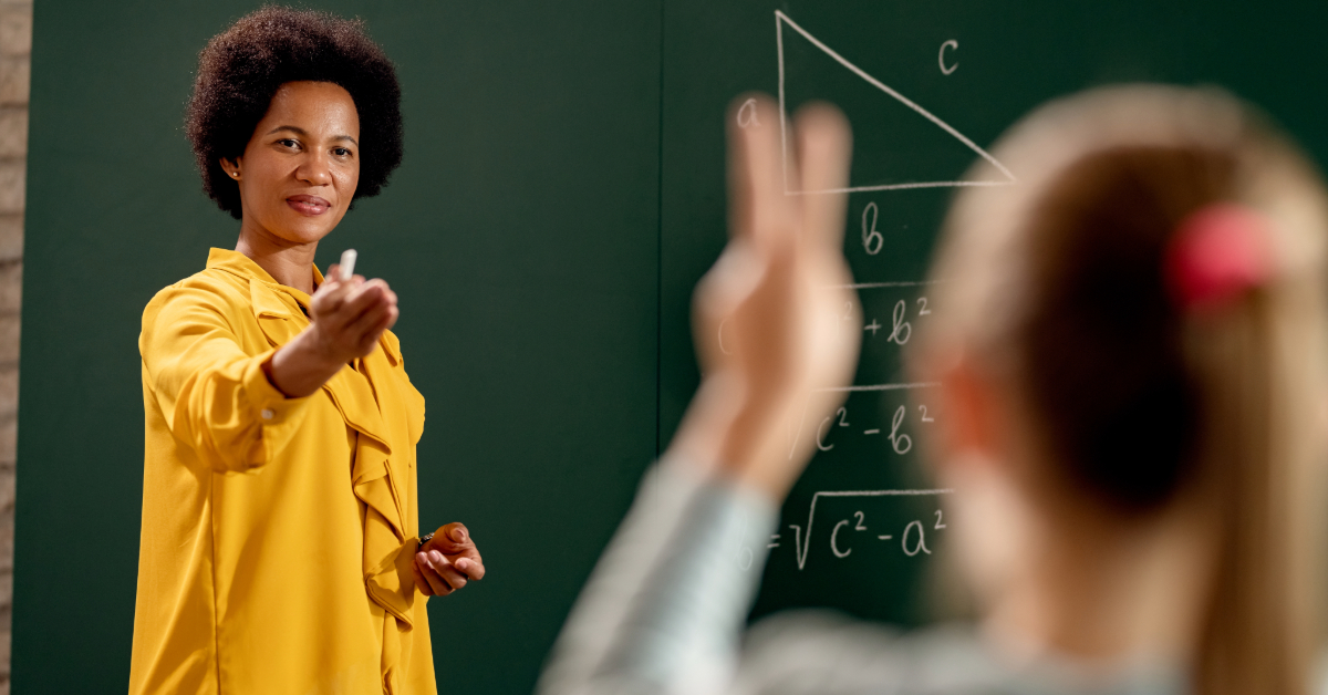 African American teacher asking a question and aiming at elementary student in the classroom.