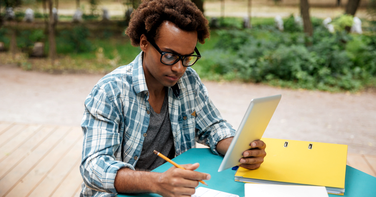 Serious Black man writing and learning in the park