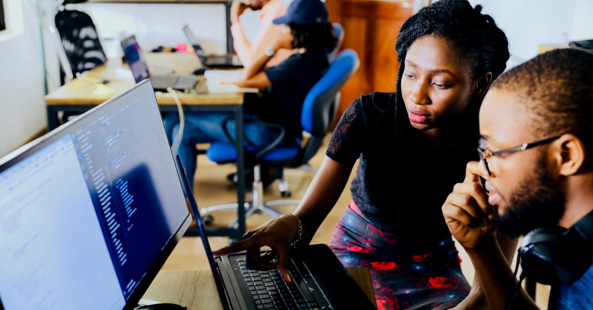 A black female student points to a computer while a black man