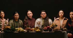 Young Indigenous women sitting at a Thanksgiving table; screen grab from Teen Vogue